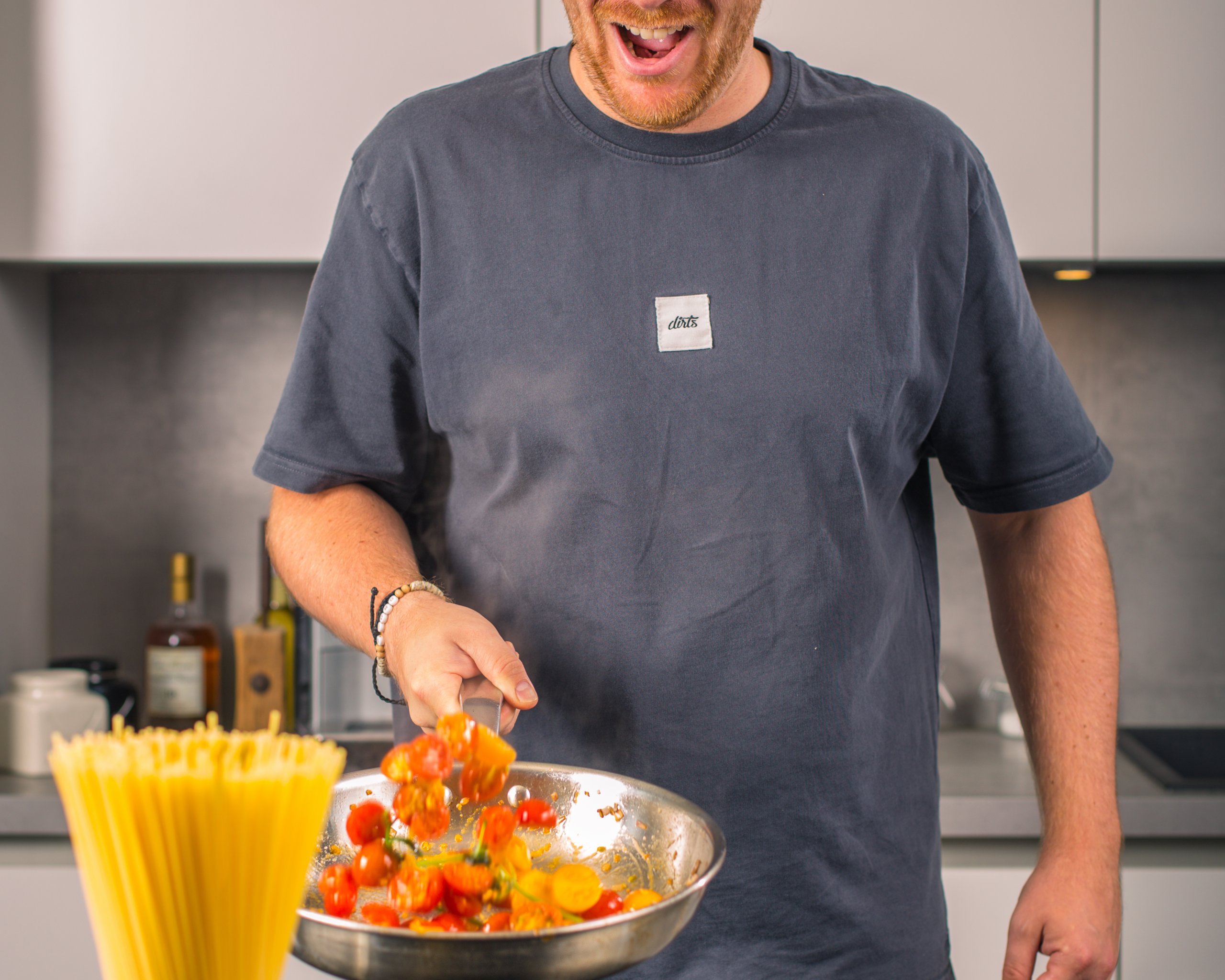 Benne Benzing schwenkt Tomaten lachend in der Pfanne