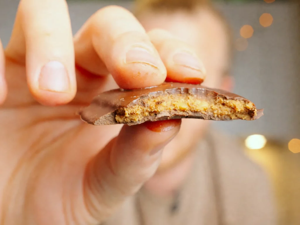 Blätterkrokant mit Schokolade – angebissenes Stück mit Krokant-Füllung und Schokoladenrand in der Hand