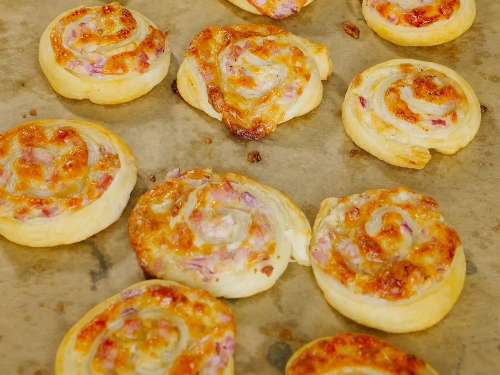 Blätterteigschnecken Elsässer Art mit Schinken-Käse-Füllung auf Backpapier