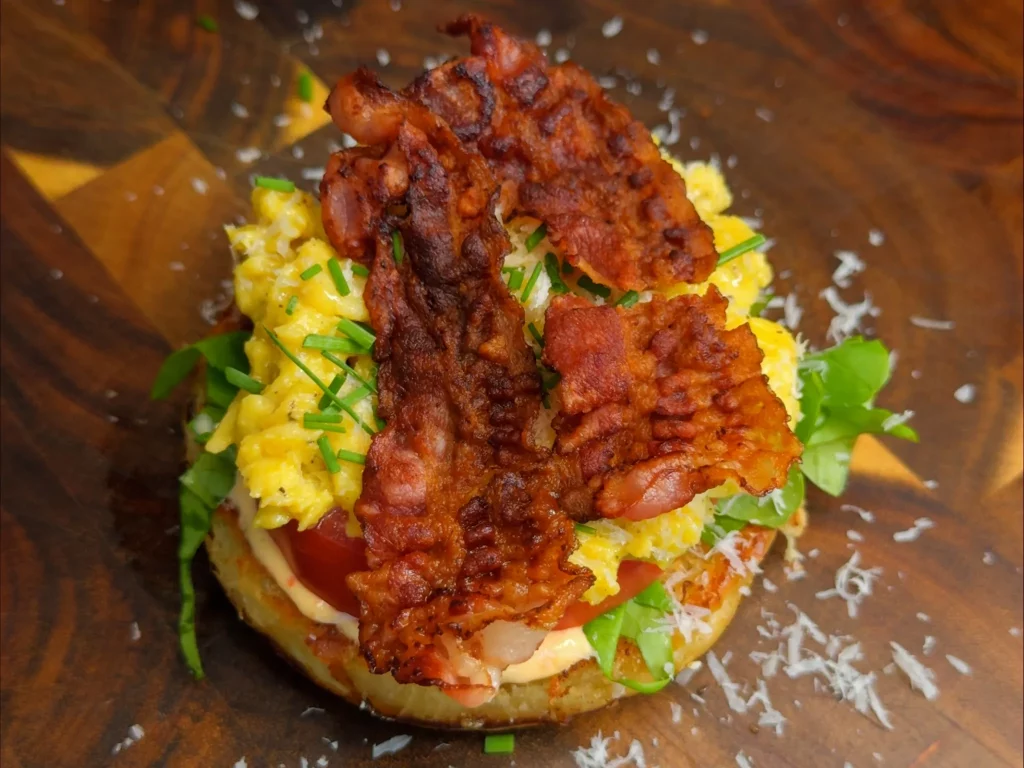 Breakfast Burger – offener Burger mit Rührei, Bacon, Tomate, Rucola und Parmesan, von oben