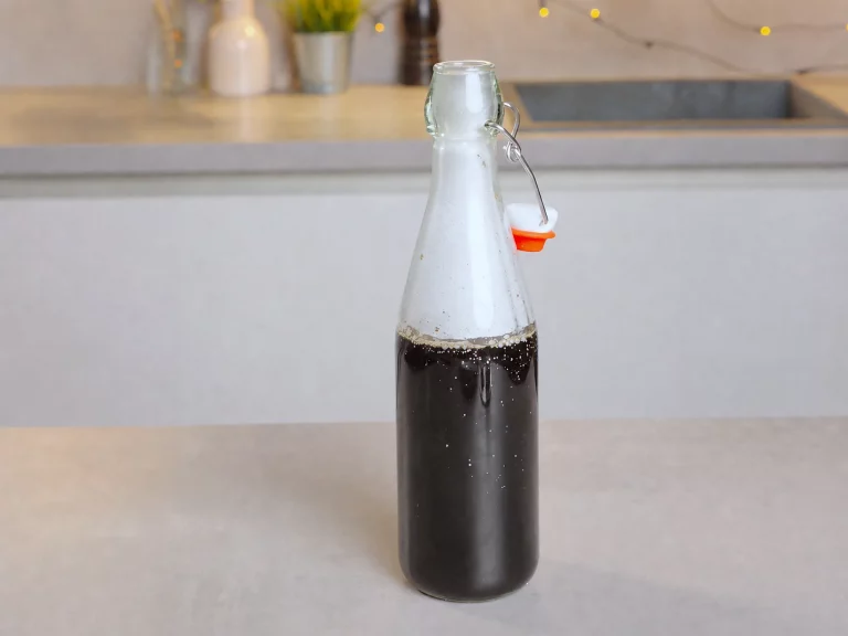 Chai-Gewürzsirup – dunkler Gewürzsirup in verschlossener Glasflasche auf der Arbeitsplatte