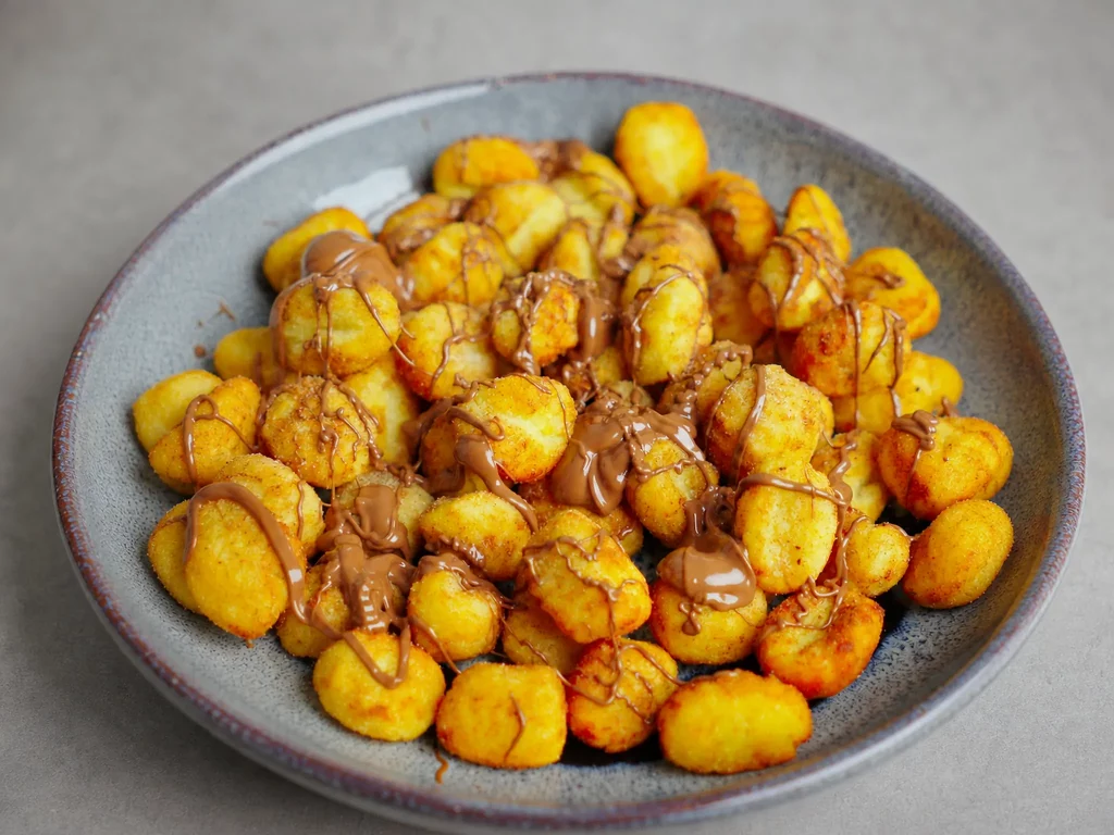 Churros Gnocchi mit Zimtzucker und Nuss-Nougat-Creme auf einem Teller