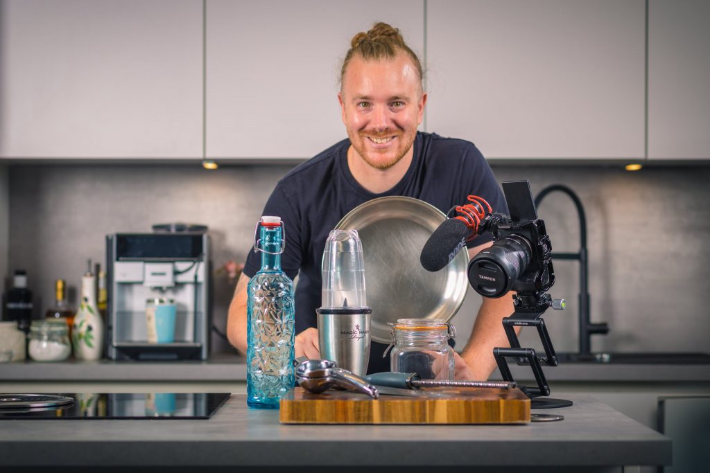 Benne Benzing mit Mixer, Pfanne, Kamera und Gläsern auf der Kücheninsel