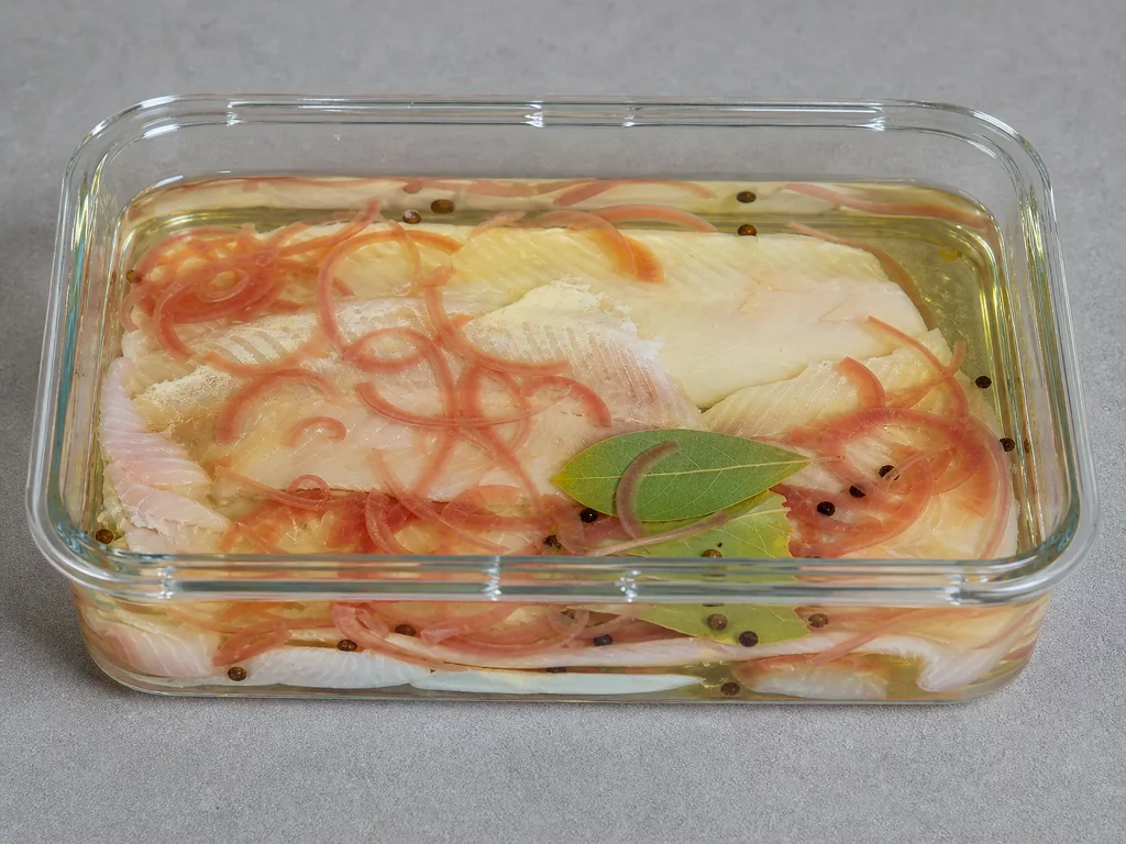 Forellenfilets in Matjeslake mit roten Zwiebeln und Gewürzen in einer Glasschale