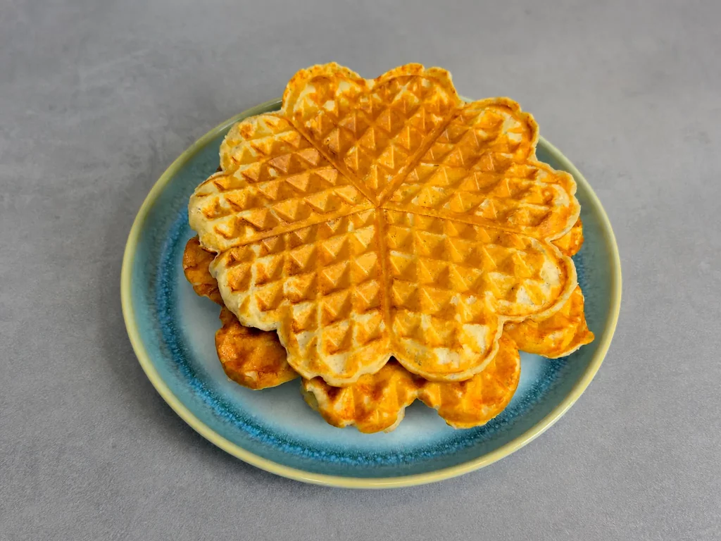 High Protein Waffeln – gestapelte Herzwaffeln, goldbraun gebacken, auf blauem Teller
