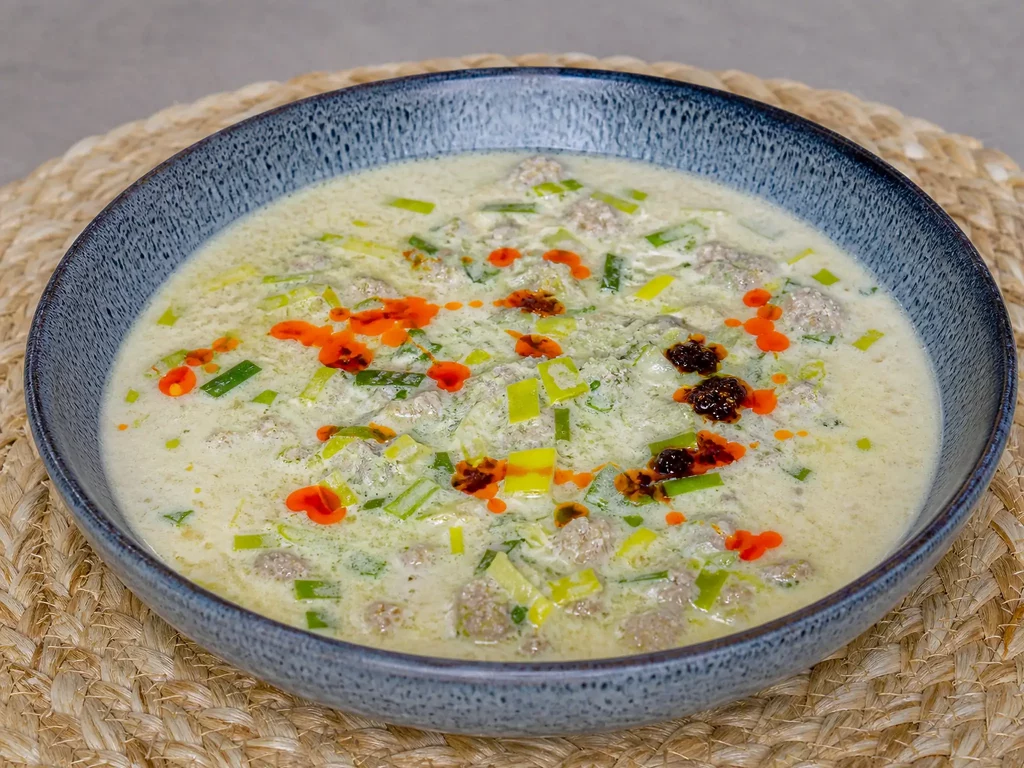 Käse-Lauch-Suppe mit Hackfleisch in einer Schale, mit Chiliöl beträufelt