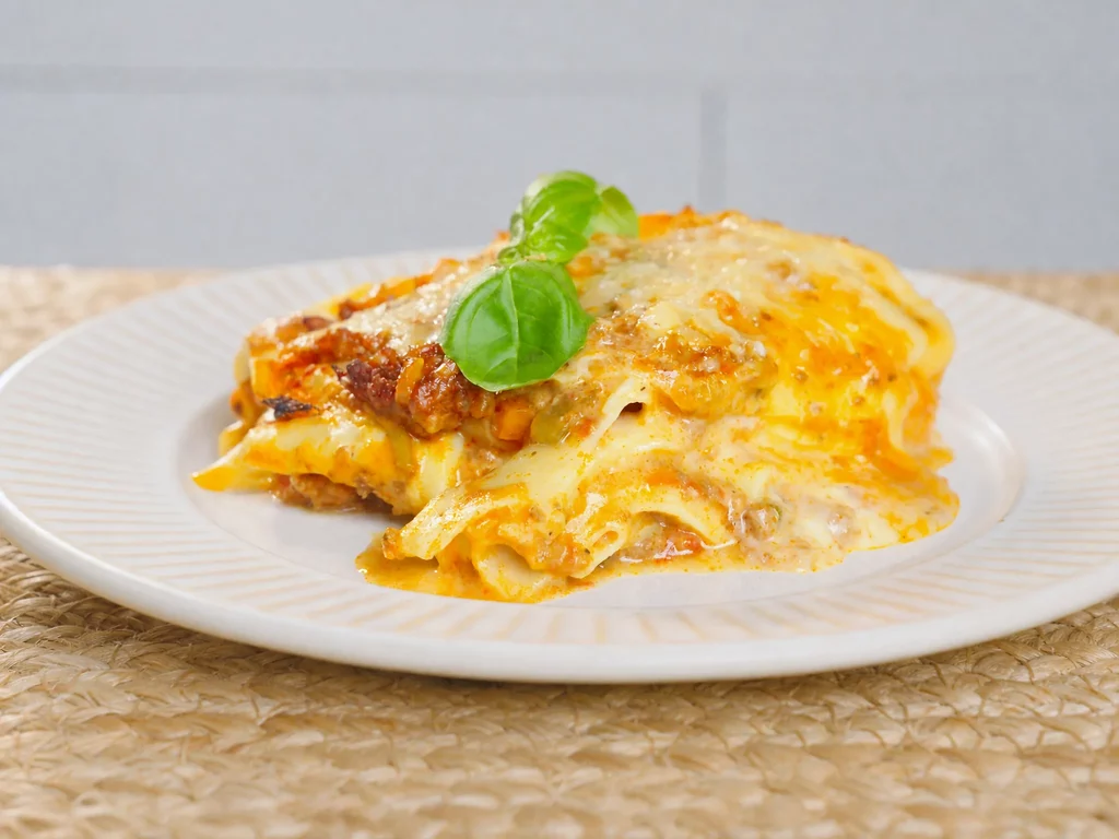 Lasagne mit selbstgemachter Pasta – angeschnittenes Stück mit Bolognese, Bechamel und Basilikum