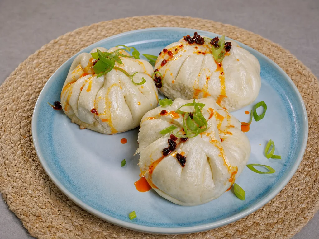 Lazy Bao gedämpft und gebraten mit Chiliöl und Frühlingszwiebeln auf Teller