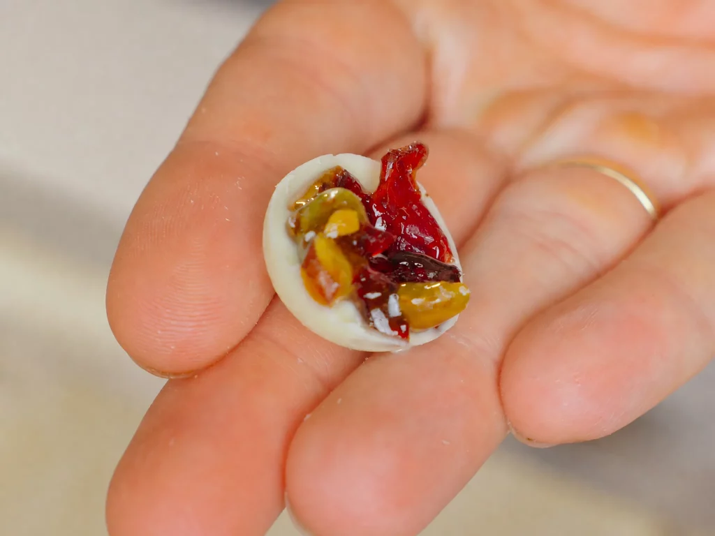 Mini Florentiner 2.0 – Schokoladentaler mit Pistazien-Cranberry-Krokant, in der Hand gehalten