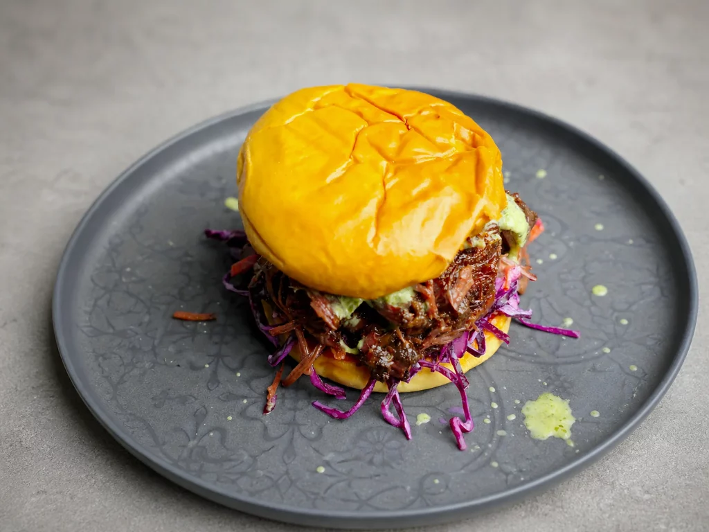 Ochsenbacken Fusion Burger – gezupftes, glasiertes Ochsenbacken auf Burger-Bun mit Rotkrautsalat, schräg von oben