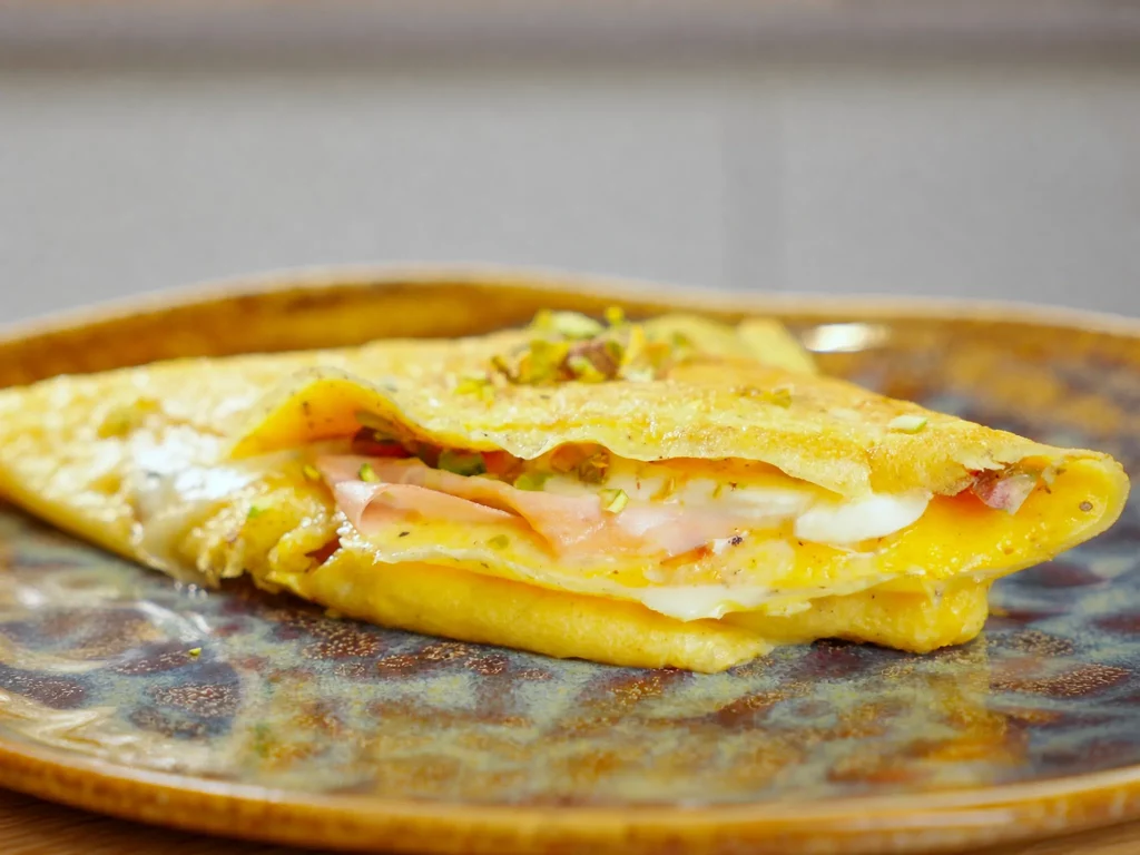Omelette-Wrap Italien Style, gefüllt mit Schinken, Mozzarella, Tomaten und gehackten Pistazien