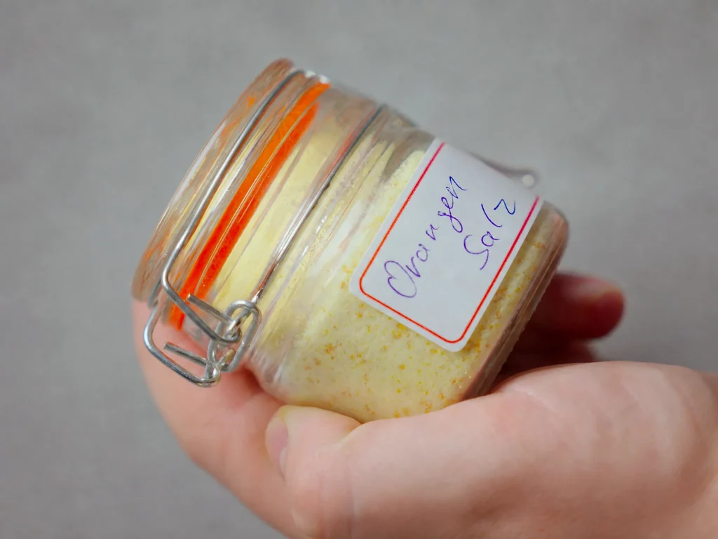 Orangensalz im Bügelglas, in der Hand gehalten, mit handbeschriftetem Etikett