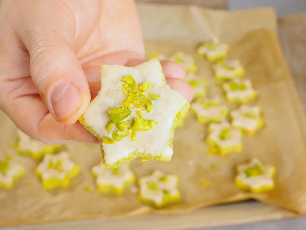 Pistazien-Sterne mit Zuckerguss und gehackten Pistazien, in der Hand gehalten