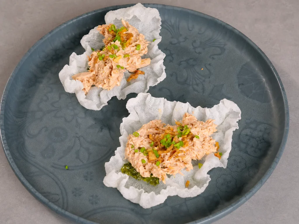 Reispapier-Cracker mit cremigem Thunfischsalat und Frühlingszwiebeln, zwei Stück auf blauem Teller