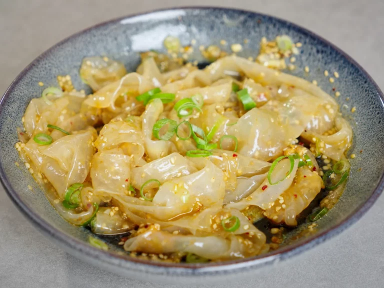 Reispapier-Nudeln in glänzender Sesam-Chili-Sojasauce mit Frühlingszwiebeln in einer Keramikschale