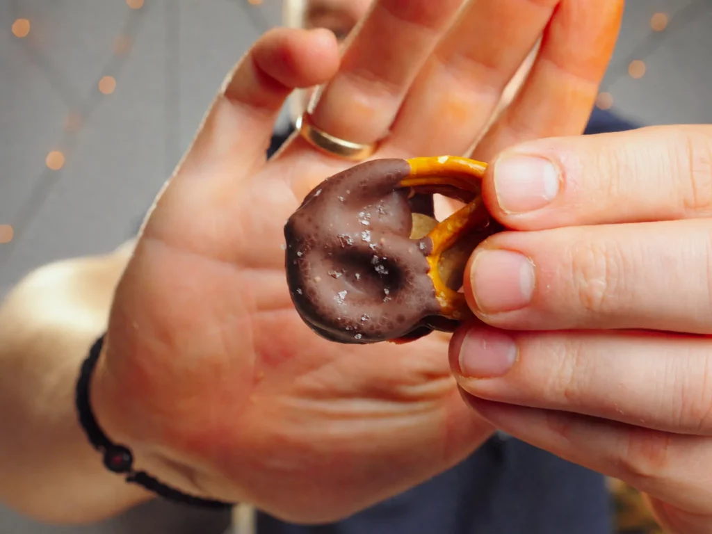 Salted Caramel Bretzel Bites – schokolierte Brezel-Sandwiches mit Karamell und Salzflocken in der Hand