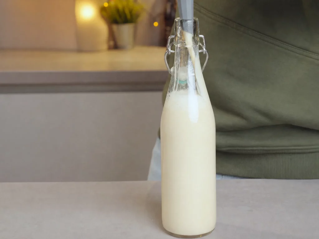 Weißer Schokoladenlikör mit Goldglanz – cremiger Likör wird in eine Bügelverschlussflasche gefüllt