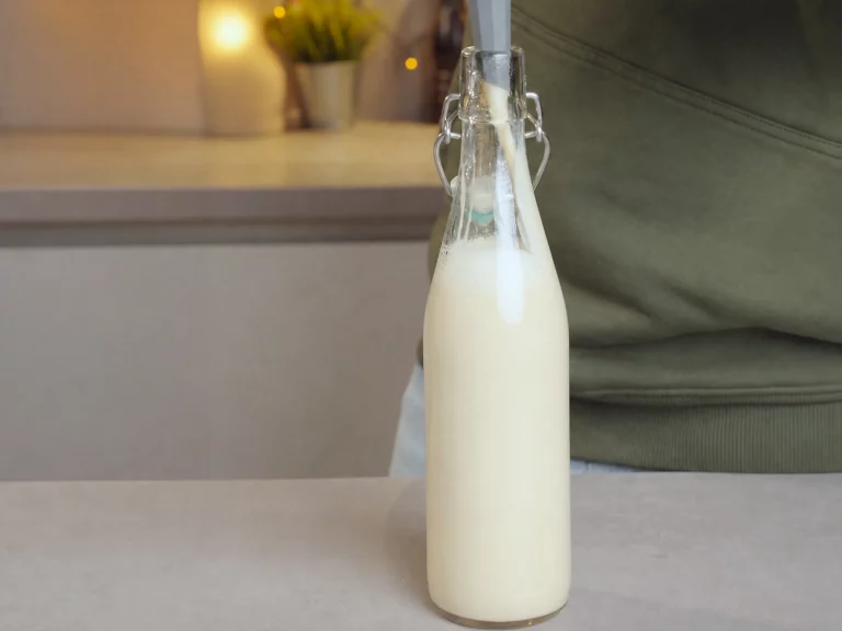 Weißer Schokoladenlikör mit Goldglanz – cremiger Likör wird in eine Bügelverschlussflasche gefüllt