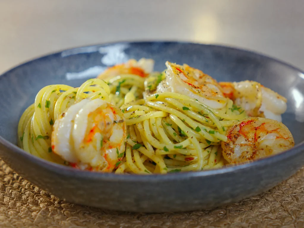 Zitronen-Garnelen-Pasta – Spaghetti mit gebratenen Garnelen und Petersilie in grauer Schale, schräg von oben